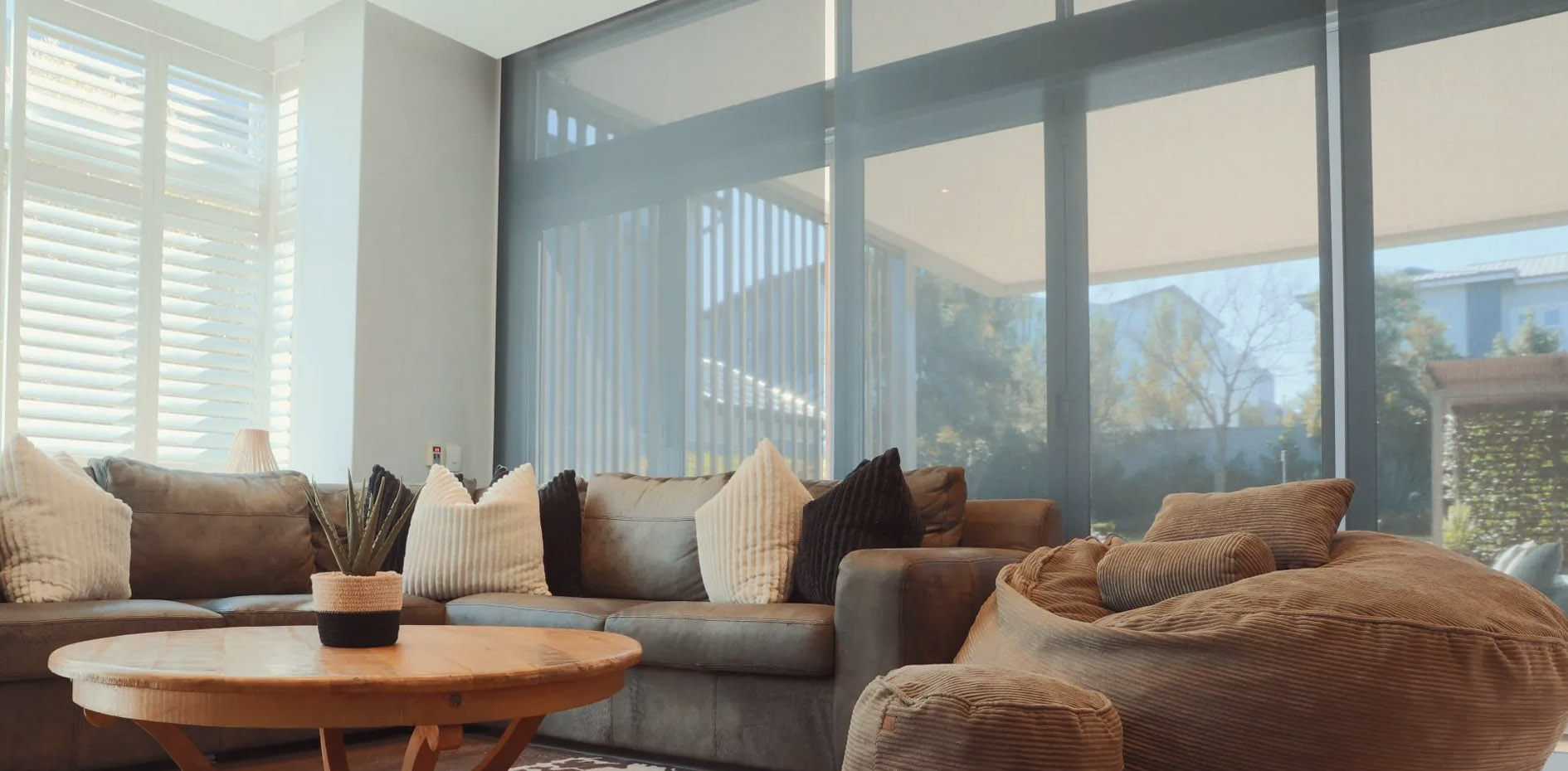 Professional installation of custom curtains and blinds, featuring white plantation shutters and sheer roller blinds for a luxury residential lounge in Johannesburg by edge.ids.